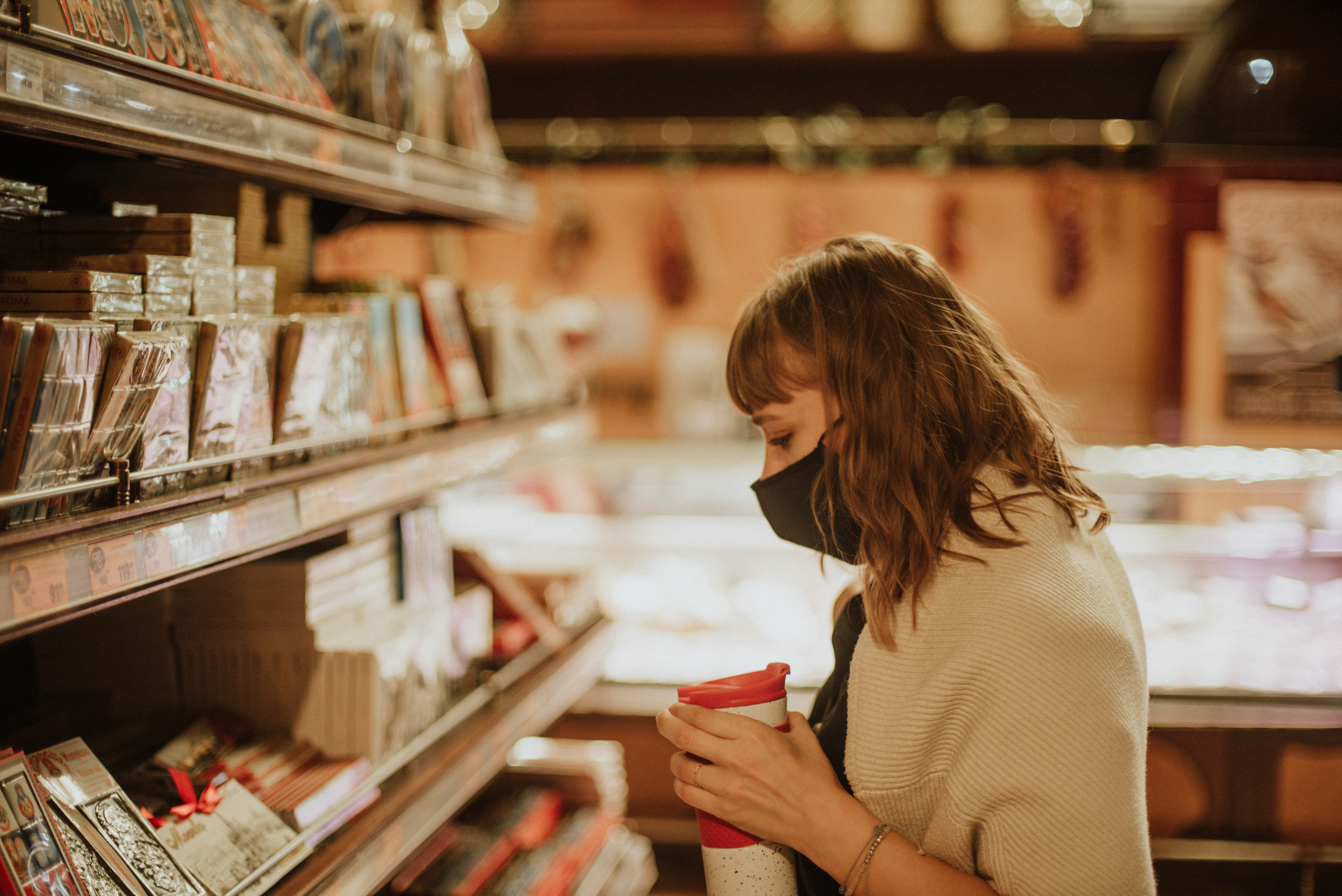 woman in white sweater holding red cup